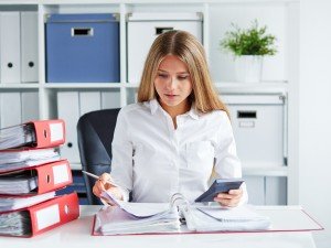 Beautiful business woman calculates tax at desk in office