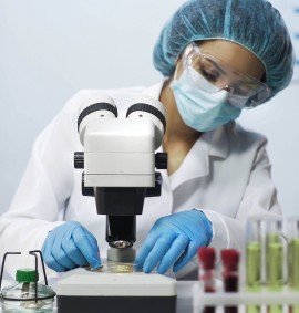 Biracial lab analyst viewing samples of bacteria on microscope, virology