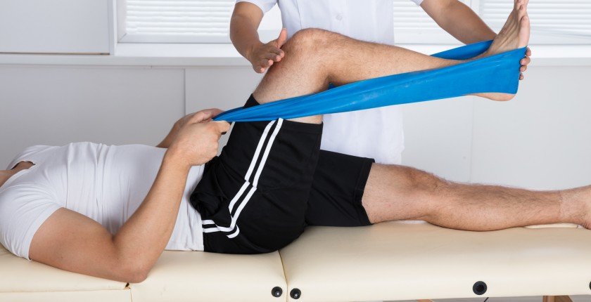 Physiotherapist Helping Patient While Stretching His Leg
