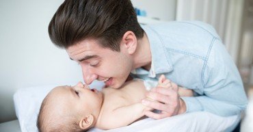Father In Nursery At Home Changing Baby Sons Daiper
