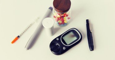 medicine, diabetes and health care concept - close up of glucometer, insulin pen, drug pills and other diabetic tools on table