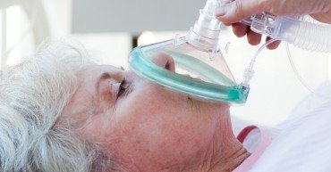 Senior patient receiving oxygen mask in a hospital