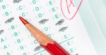 A graded test form with red scoring pencil indicates acheivement and success in education.
