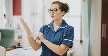 Female nurse putting on a glove