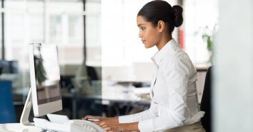 Multi ethnic business woman working with computer at the office. Focused young businesswoman checking email with laptop. Office worker typing on a keyboard in her office.