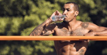 Afro Athlete Relaxing After Intense Workout, Drinking Water Outdoors