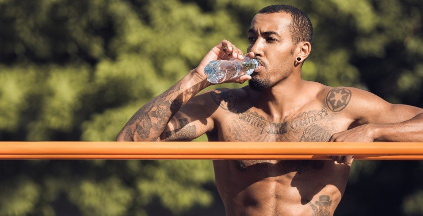 Afro Athlete Relaxing After Intense Workout, Drinking Water Outdoors