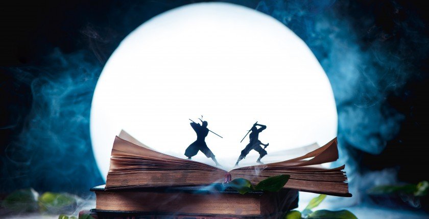 An open book with two ninja warrior silhouettes fighting in full Moon. Reader imagination and writing inspiration concept with copy space
