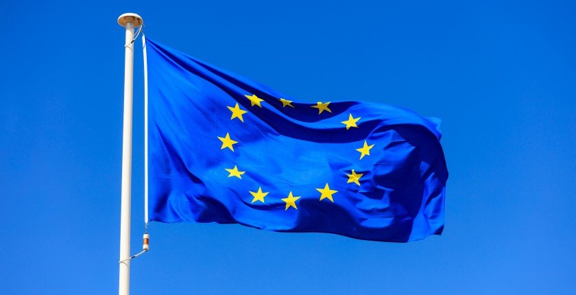 EU flag. European Union flag on a flagpole waving on a bright blue sky background